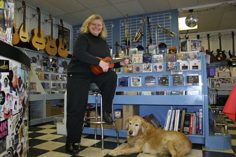 Vashon Island Music owner Karen Eliasen plays the ukulele while Scout listens.