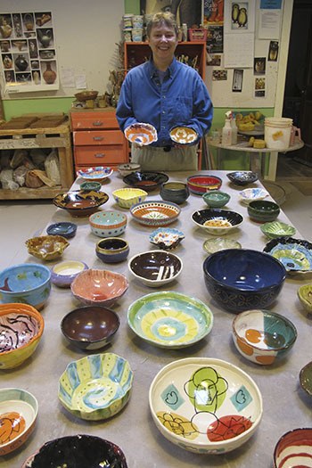 Potter Liz Lewis with a table of finished bowls for the fundraiser.