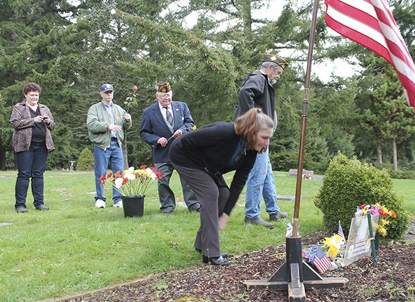 Susan Lofland (front) places a flower on Robert Bennedsen’s grave at the Vashon Cemetery. Behind her are Lisa Devereau