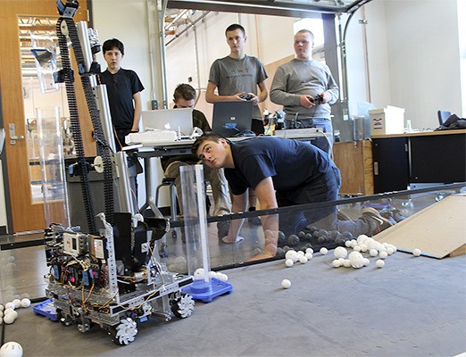 Michael Clark (front) watches the robot while teammates control it at practice.