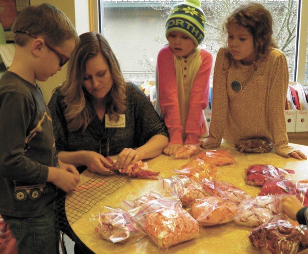 Jackie Merrill works with second-grade students on a fiber collage project for the auction.