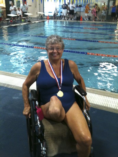 Bonnie Raume poses with her gold medal at the Washington State Senior Games. She holds up her right leg