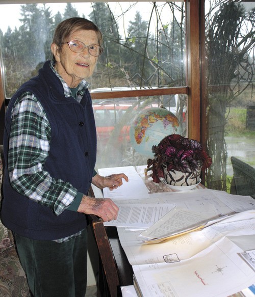 Margaret Rosser stands before a table filled with documents her daughter Gay has collected.