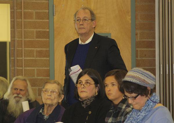 Tom Bangasser stands behind his wife Melissa while votes on a motion to remove him from the community council board are tallied.