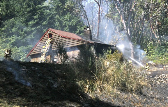 VIFR crews work to put out a blaze at a small home on Maury Island Monday afternoon.