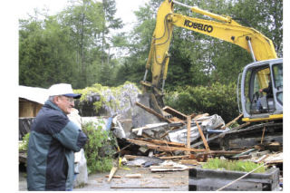 Mike Cunningham surveys the scene while Lewis Roggenbuck works the backhoe.