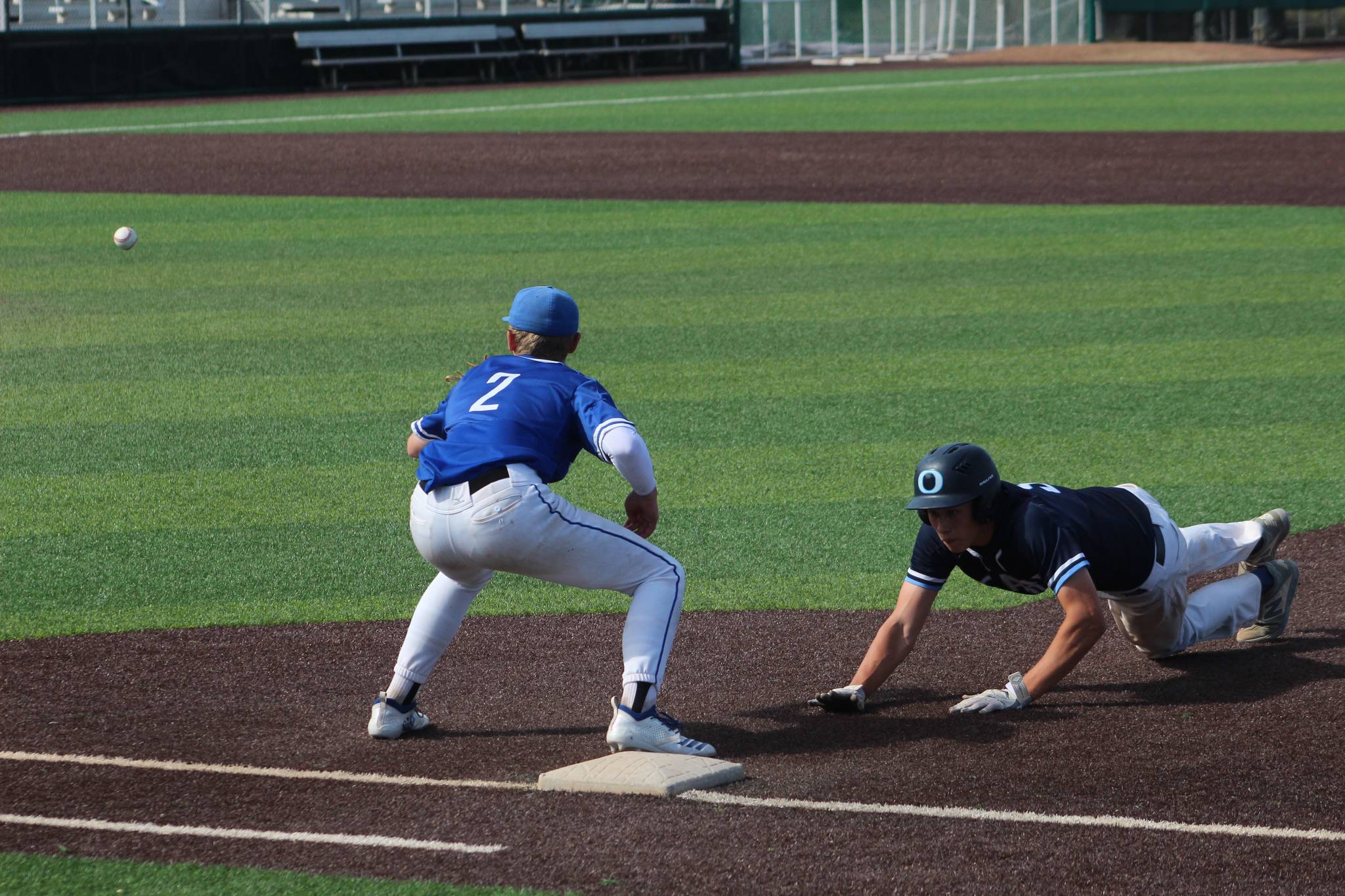 Federal Way’s Jack Arsenian anticipates a catch as an Olympia player leaps back to first base at the state quarterfinals in in Everett in May 2019. Olivia Sullivan/staff photo