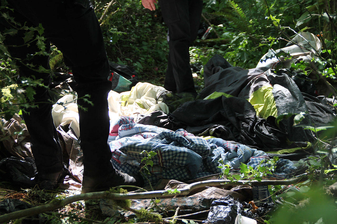 King County Sheriff’s Deputies walk through an encampment in Island Center Forest in 2018 (Paul Rowley/Staff Photo).