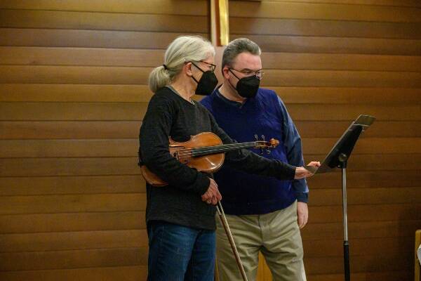 Gaye Detzer, violin soloist for “Seashore” by Bronwyn Edwards, confers with Maestro Gary Cannon during a rehearsal for Vashon Island Chorale’s upcoming concert (John de Groen Photo).