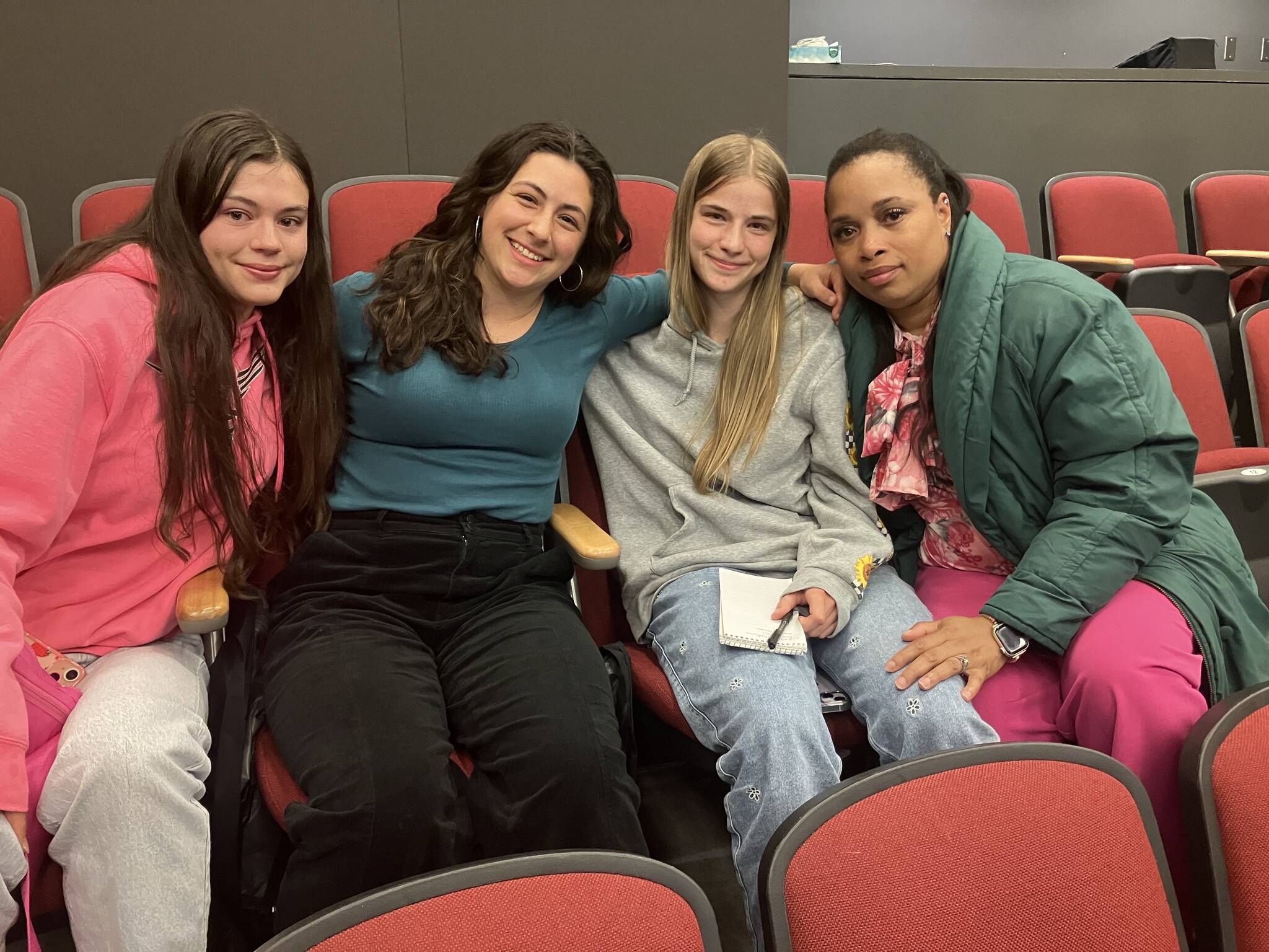 Elizabeth Shepherd Photo
(Left to right) Alana Bass, Amelia Medeiros, Annabelle Moeckel, and school nurse and track coach Brandi Greenidge sit together after the school board meeting. In an emotional appeal, the three students urged the board not to cut Greenidge’s job.