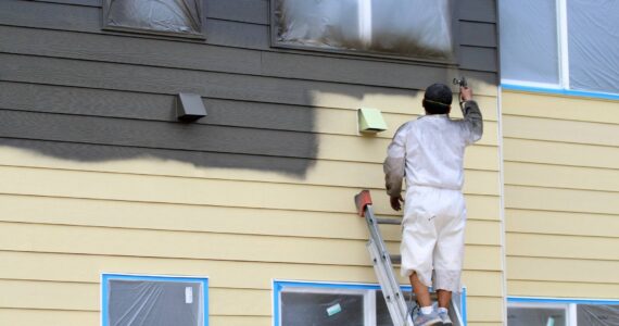 A worker paints a building on July 17 at Vashon HouseHold's upcoming Island Center Homes. (Alex Bruell photo)