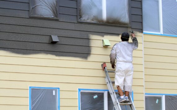 A worker paints a building on July 17 at Vashon HouseHold's upcoming Island Center Homes. (Alex Bruell photo)