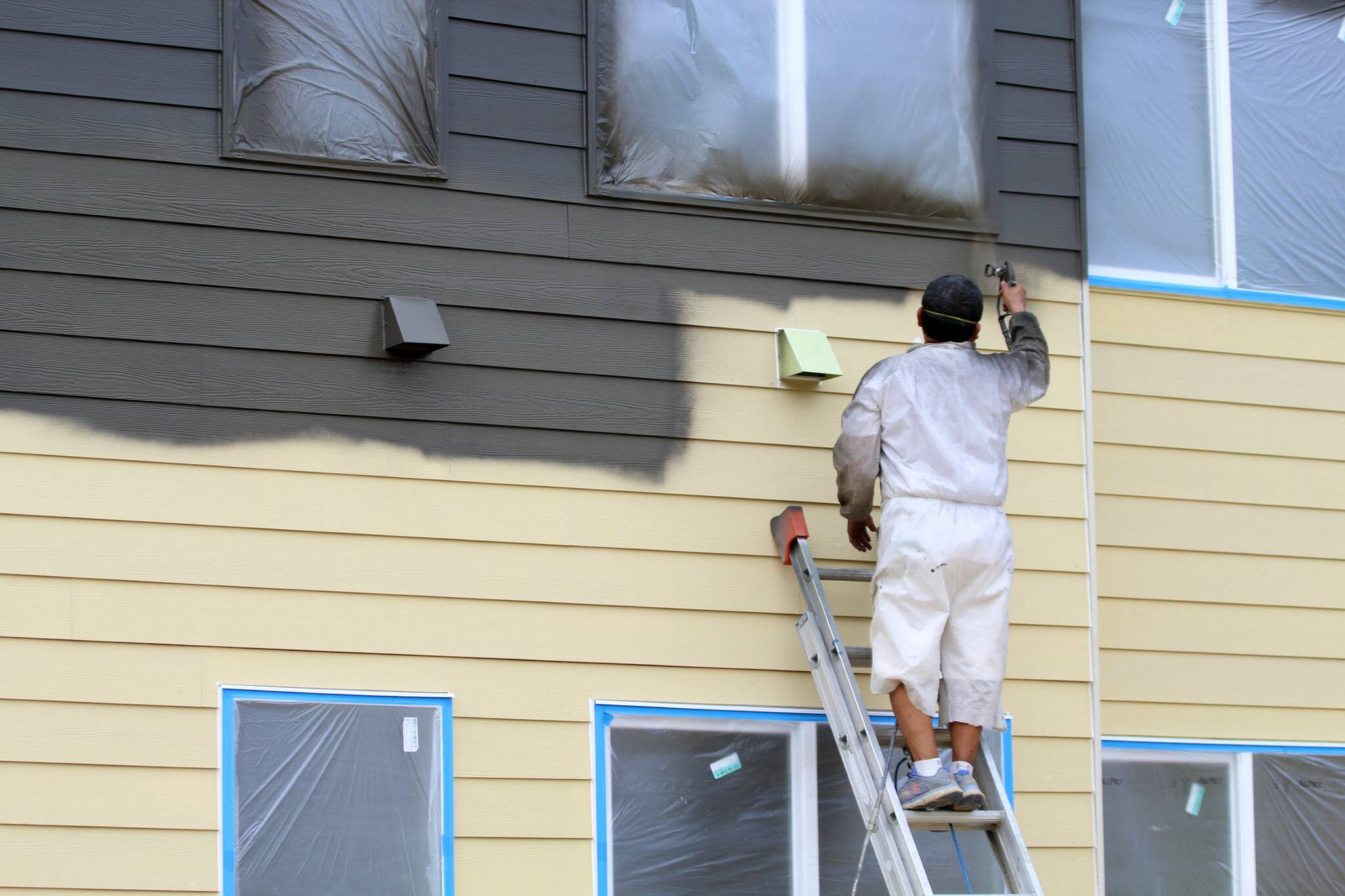 A worker paints a building on July 17 at Vashon HouseHold’s upcoming Island Center Homes. (Alex Bruell photo)