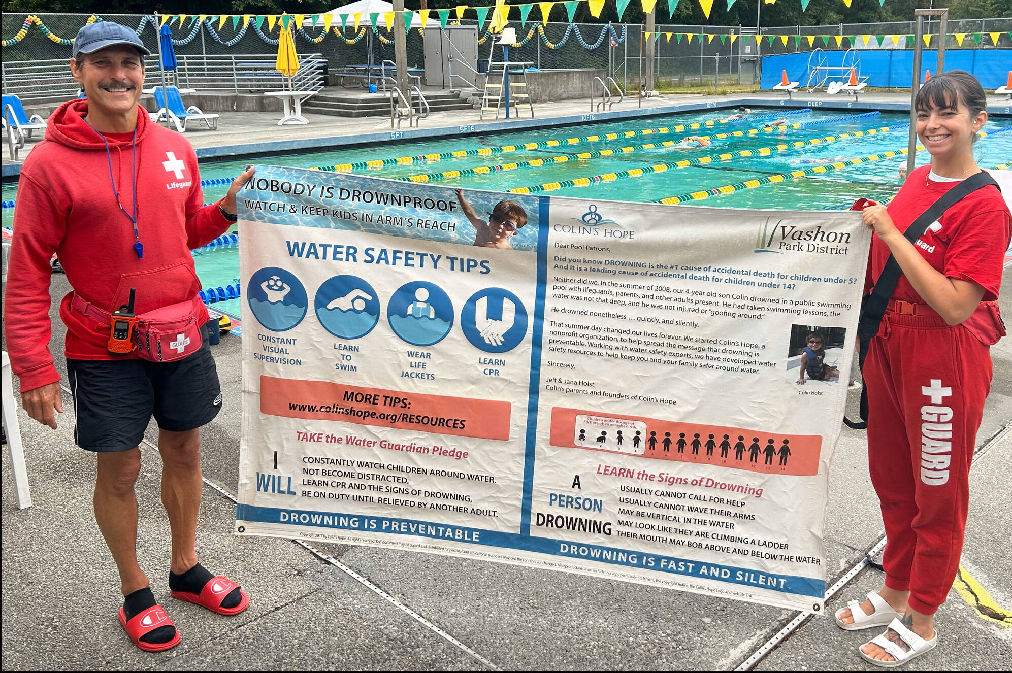 Megan Yeager (right), Vashon Park District lifeguard, swim instructor, and Vashon Seals Swim Team assistant coach, holds a banner of water safety tips with lifeguard colleague Michael “Wish” Wishkoski. “At a bare minimum, every child should learn how to float,” Yeager said. (Courtesy photo.)