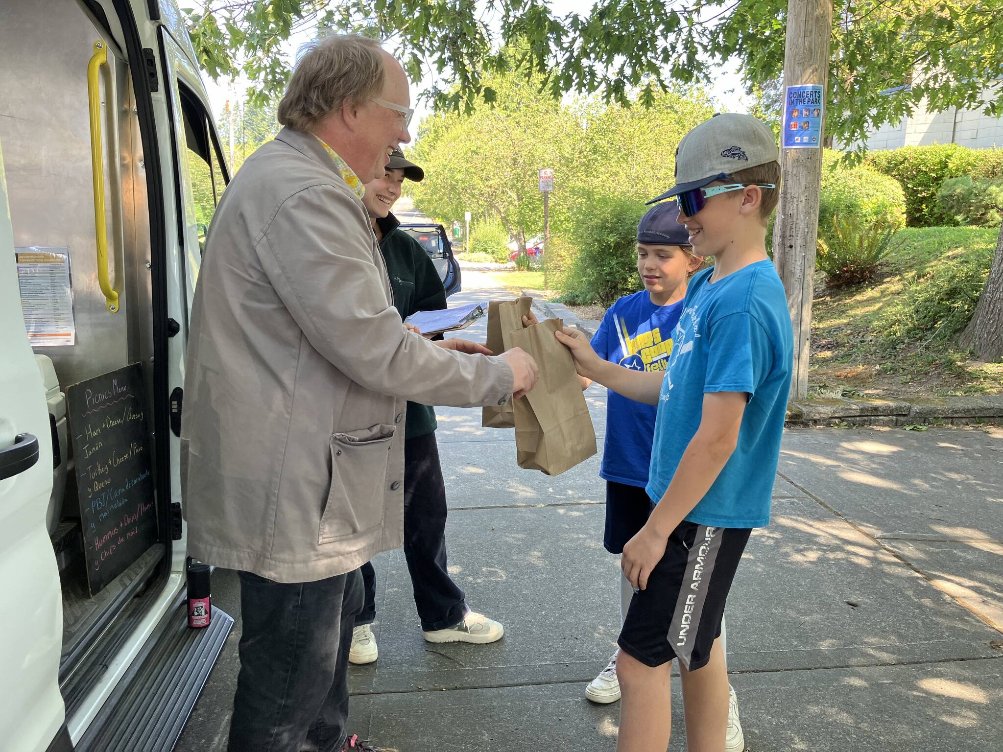 Savvy island kids grab a free lunch from Jim Marsh and Clara Atwell at Vashon Food Bank’s Picnics in the Parks truck, which offers free weekday lunches at Ober Park and Burton Area Recreation Center (BARC). (Elizabeth Shepherd photo)