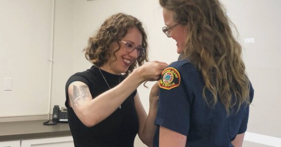 As is tradition in the fire service, Volunteer Firefighter Jenny Gogarten’s badge was pinned by her wife during the VIFR meeting, with their two children eagerly watching. (Alex Bruell photo)