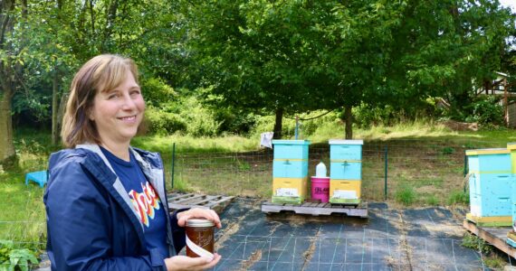 Aspen Anderson photo
Islander Jenna Riggs holds a jar of honey next to her hives on Vashon Island.