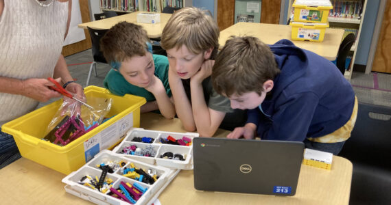 Marie Koltchak photo
(From left to right) Teacher-librarian Kathleen Lawrence, sixth-graders Skyler McMillen-Meyers and Brooks Johnson, and fifth-grader Simon Tilden open a new box of Lego materials.