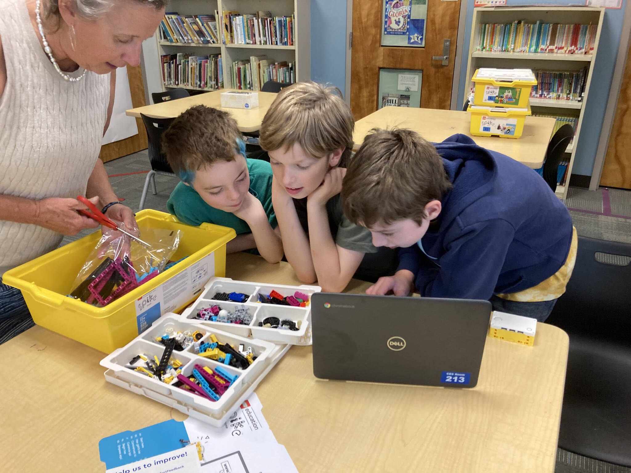 (From left to right) Teacher-librarian Kathleen Lawrence, sixth-graders Skyler McMillen-Meyers and Brooks Johnson, and fifth-grader Simon Tilden open a new box of Lego materials. (Marie Koltchak photo)