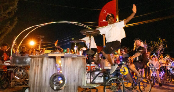 Cedar Louis and Nate Wilson motion to the crowd while rolling through town on “Grill Force One,” built by the Stupid Bike Club. (Michelle Bates photo)