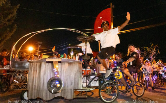 Cedar Louis and Nate Wilson motion to the crowd while rolling through town on “Grill Force One,” built by the Stupid Bike Club. (Michelle Bates photo)