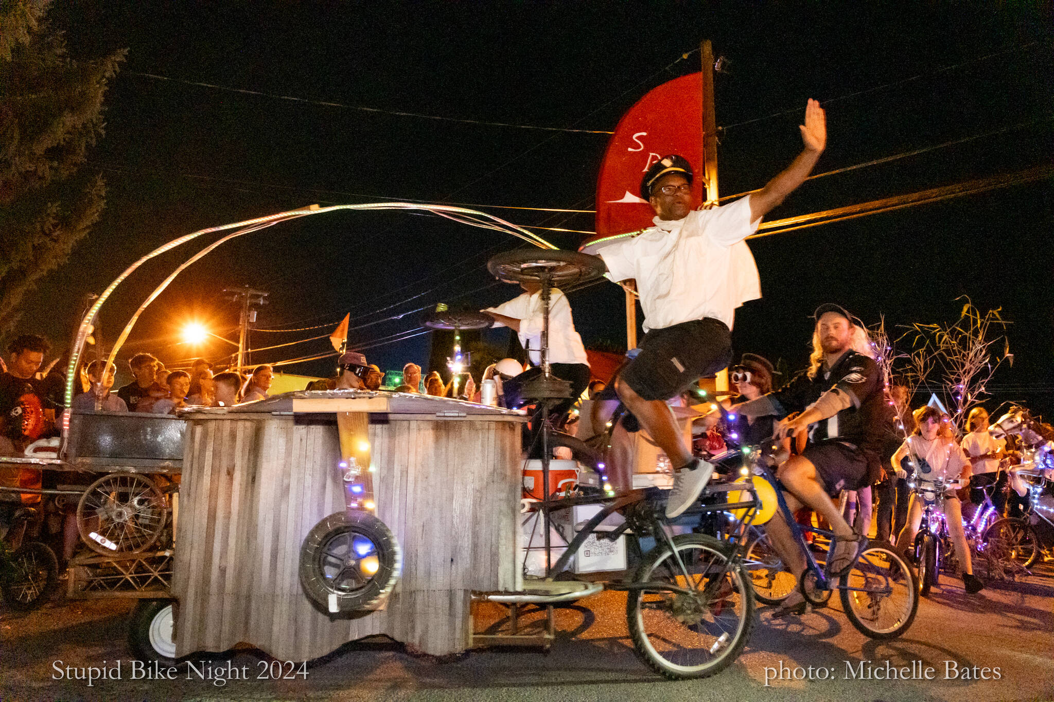 Cedar Louis and Nate Wilson motion to the crowd while rolling through town on “Grill Force One,” built by the Stupid Bike Club. (Michelle Bates photo)