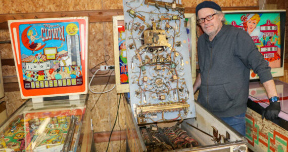 Mo Davis stands next to the inner workings of one of his pinball machines. (Aspen Anderson photo)