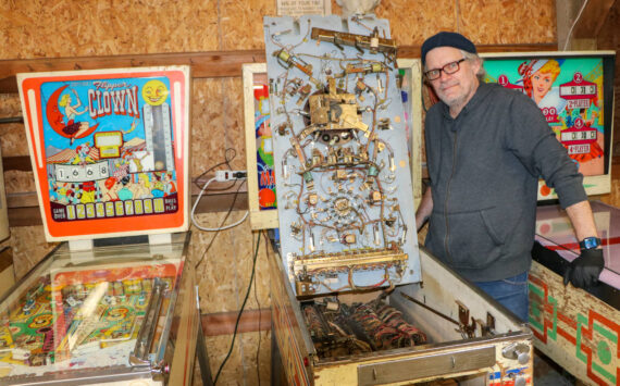 Mo Davis stands next to the inner workings of one of his pinball machines. (Aspen Anderson photo)