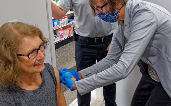 New Pharmacy Space: Vashon Pharmacy owner Tyler Young looks on as Cece Reoux vaccinates Su DeWalt. Young says: “We are very pleased with our new clinical services area. Patients appreciate the space and the privacy of being in a treatment room. It’s a big improvement.”